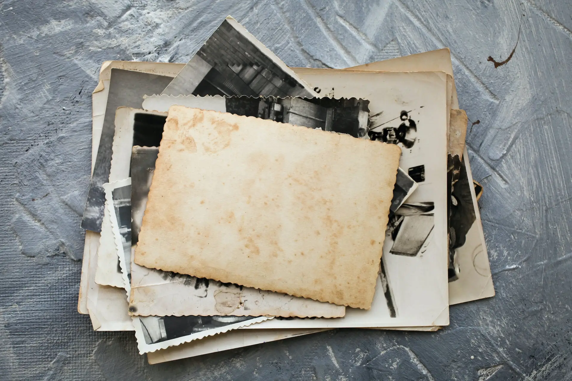 Stack old photos on grey background. Postcard rumpled and dirty vintage.