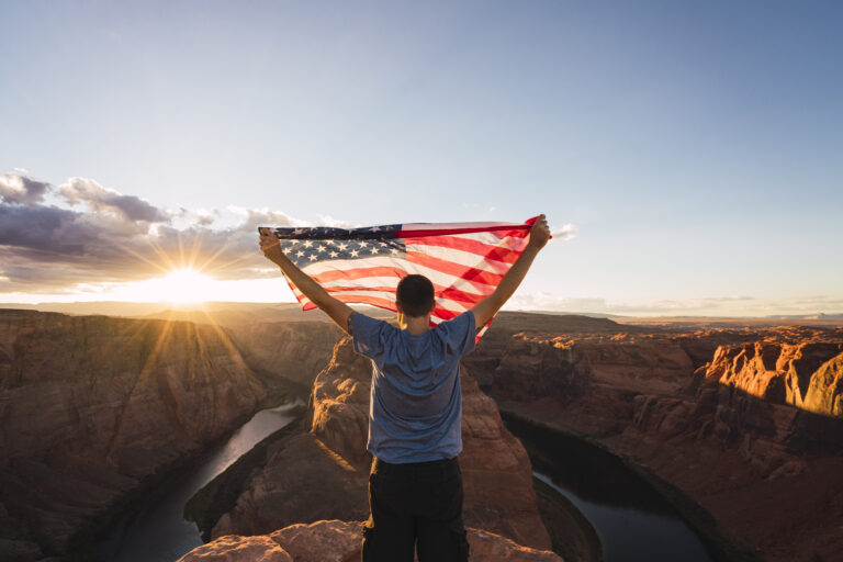 Young man on Horseshoe Bend viewpoint with American flag