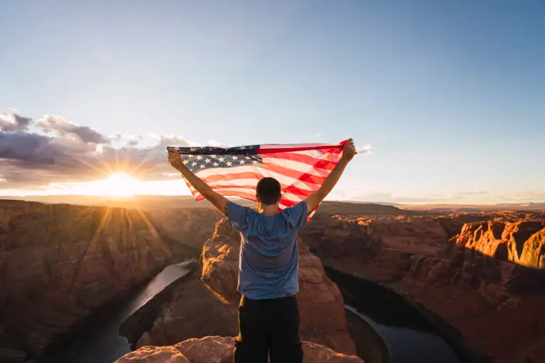 Young man on Horseshoe Bend viewpoint with American flag