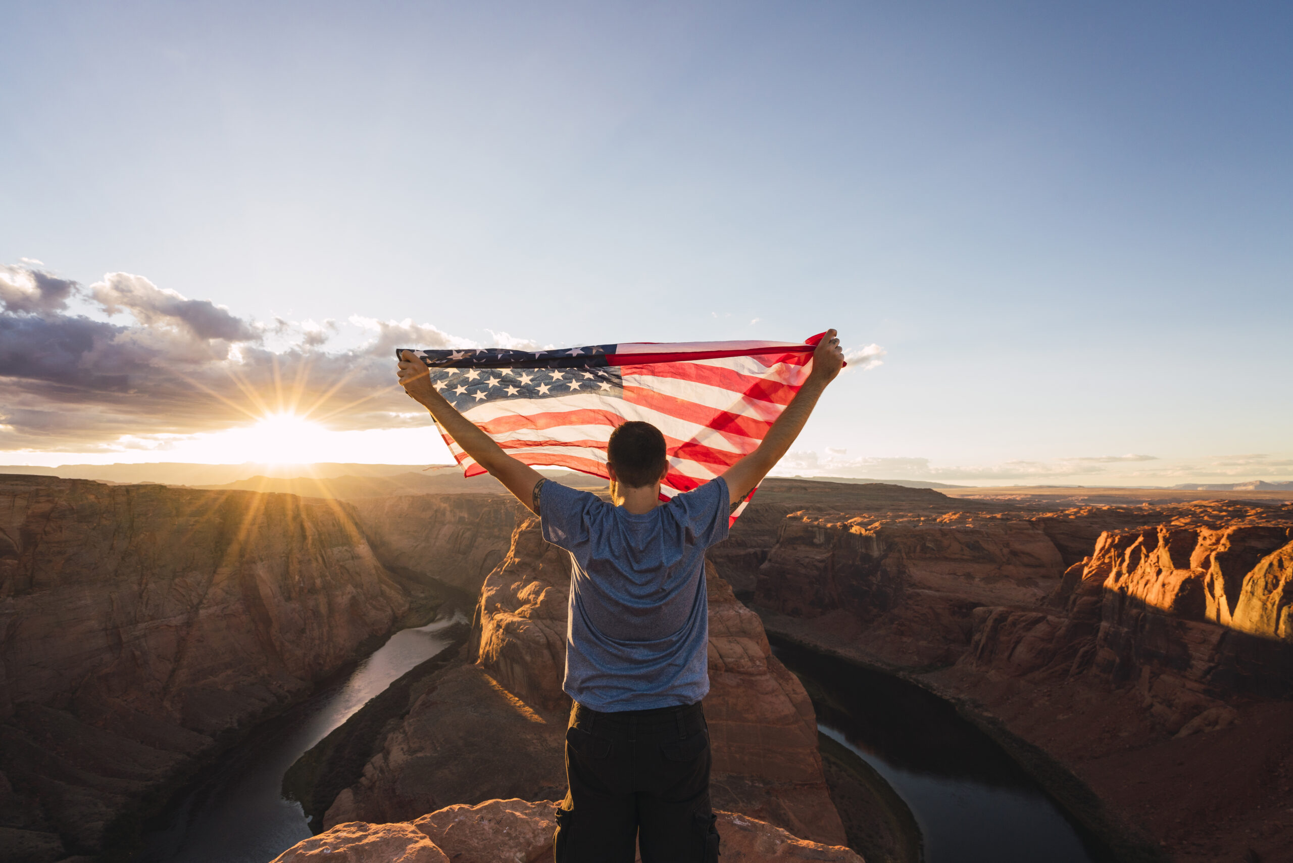 Young man on Horseshoe Bend viewpoint with American flag