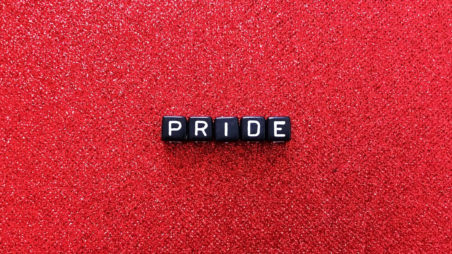 Dice spelling "pride" on red background