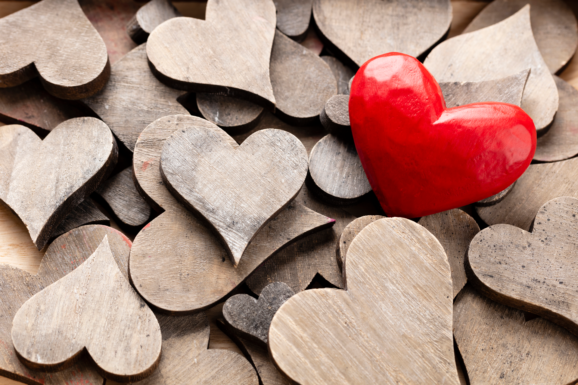 One red heart on a background of wooden hearts