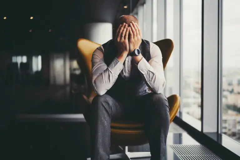 Discouraged man sitting in armchair near window