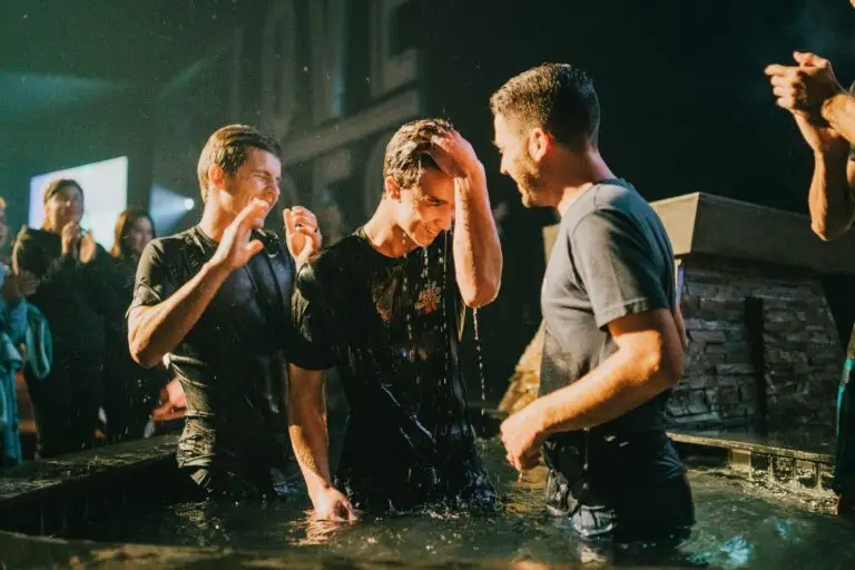 Three men standing in black baptismal pool