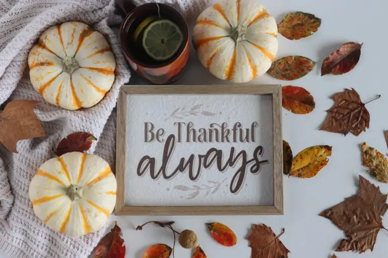 Sign saying "Be thankful always" among background of gourds and leaves