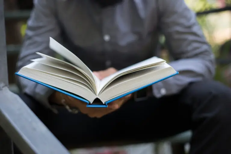 Young man reading book with blue hardback binding