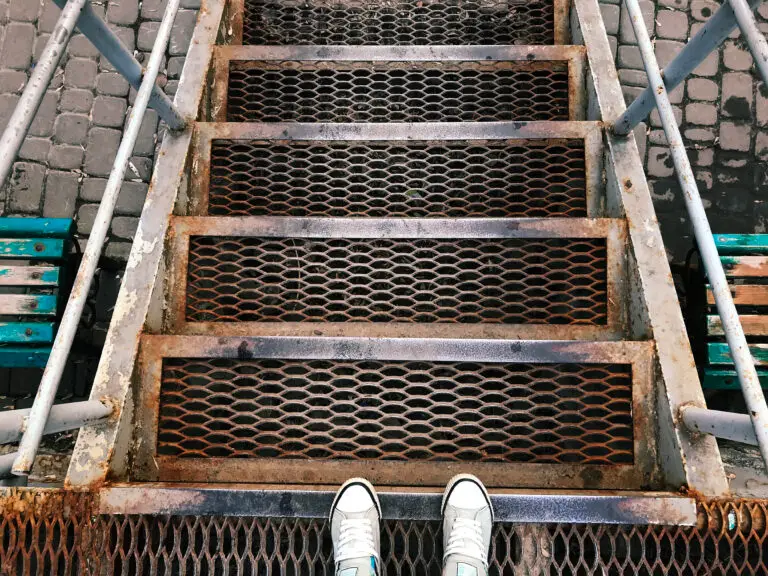 feet in white sneakers standing on metal steps