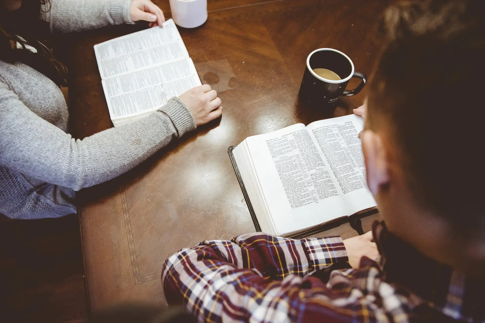 A high angle shot of a small group of people drinking coffee and reading the Bible