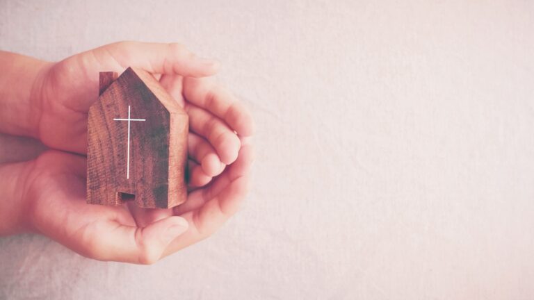 Child hands holding wooden church