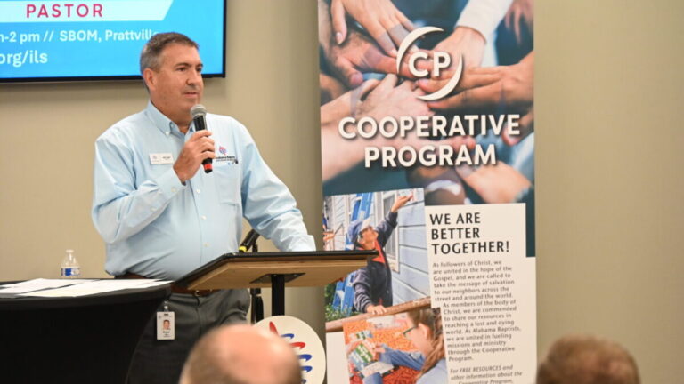 Bryan Blass stands in front of a podium holding a mic speaking to pastors on leadership